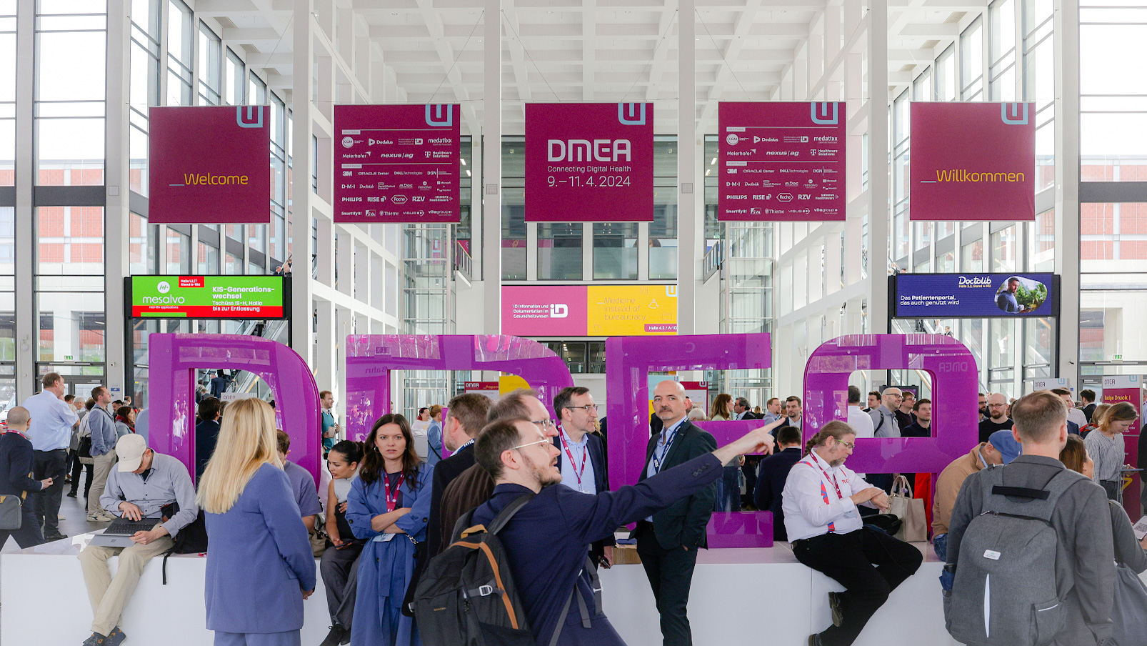 Blick in den Eingang Messe Süd der Messe Berlin mit den DMEA Buchstaben und Besucher:innen drumherum 