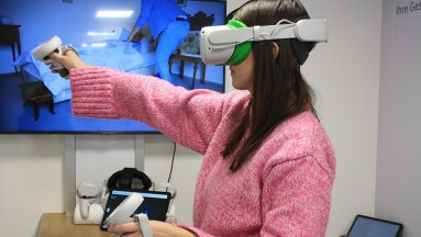 Eine Frau trägt eine VR-Brille und taucht in eine virtuelle Umgebung ein. Ihre Hände sind leicht erhoben.