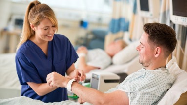 A nurse puts a patient wristband on a patient.