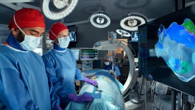 The image shows an operating room with physicians performing a procedure with digital support.