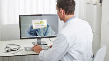 Ein Arzt sitzt an einem Bildschirm und öffnet die Software xentro von medatixx.